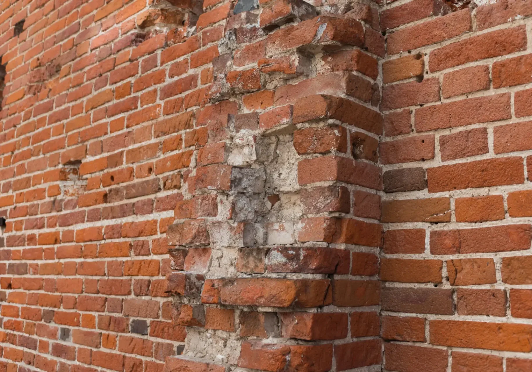 Old brick wall with damaged corner and worn mortar.